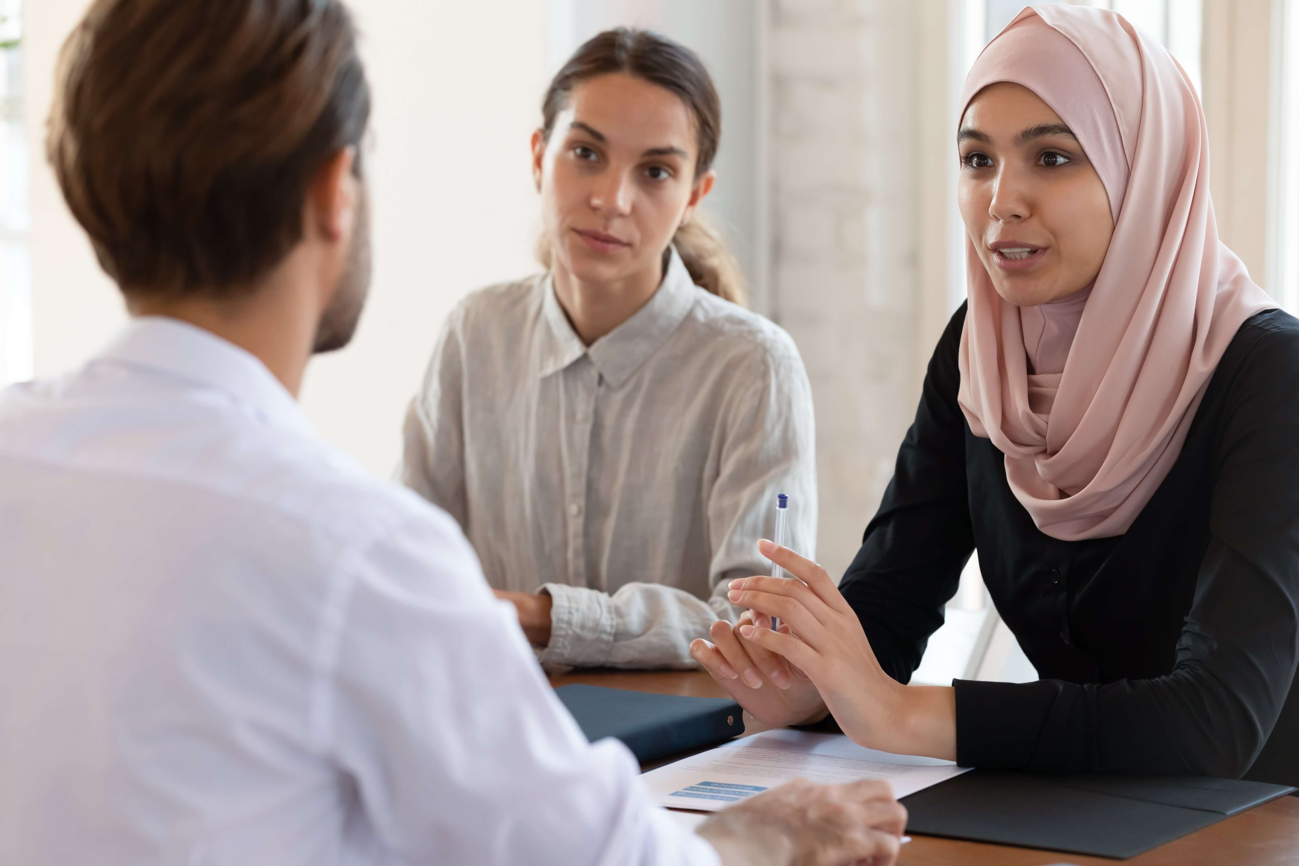 Two women and a man sat around a table having a conversation