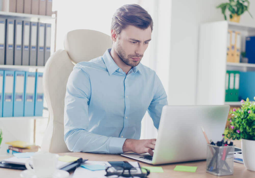 Smartly dressed man typing on a laptop