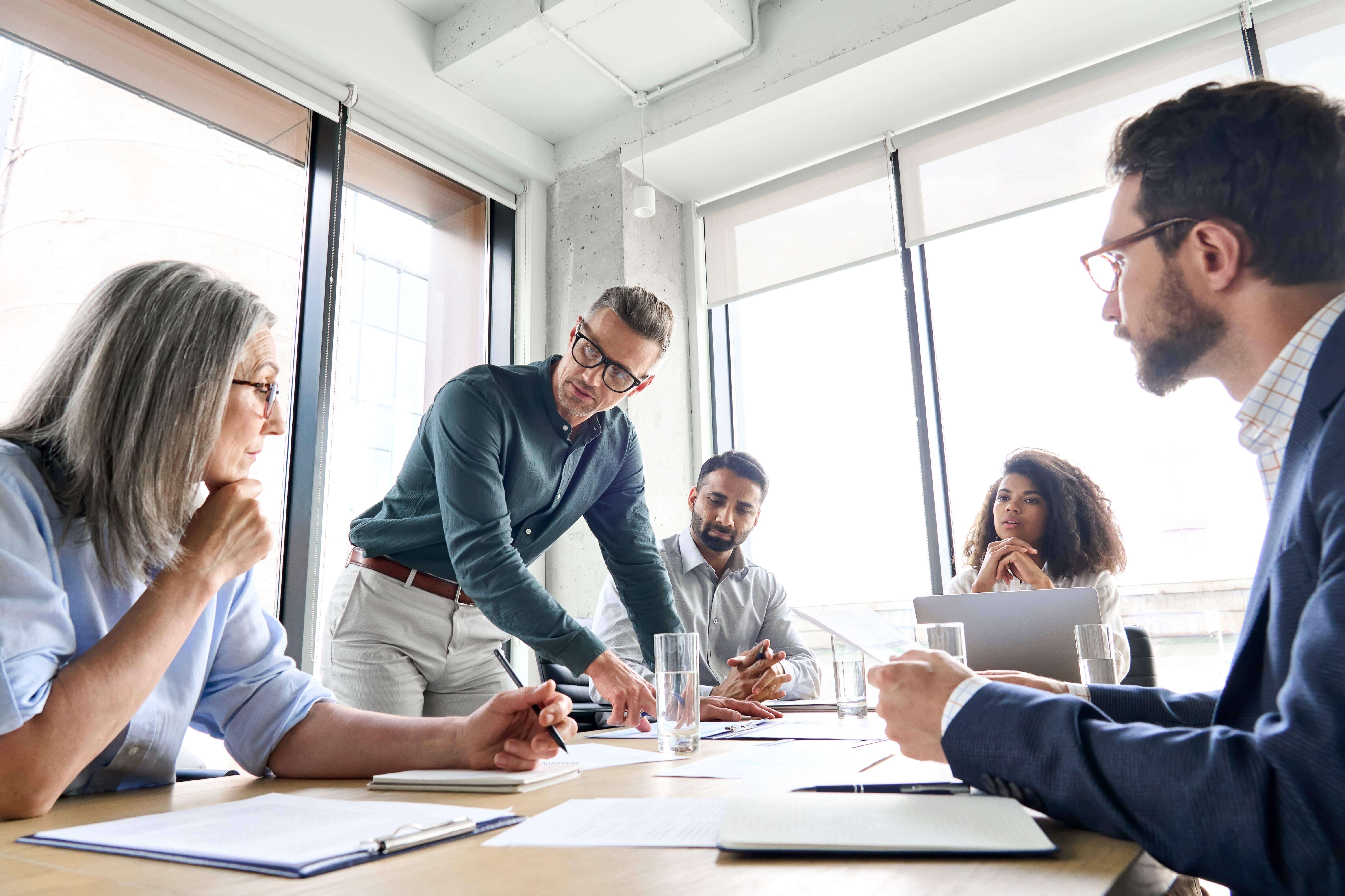 a group of people in a meeting room, discussing or reviewing work