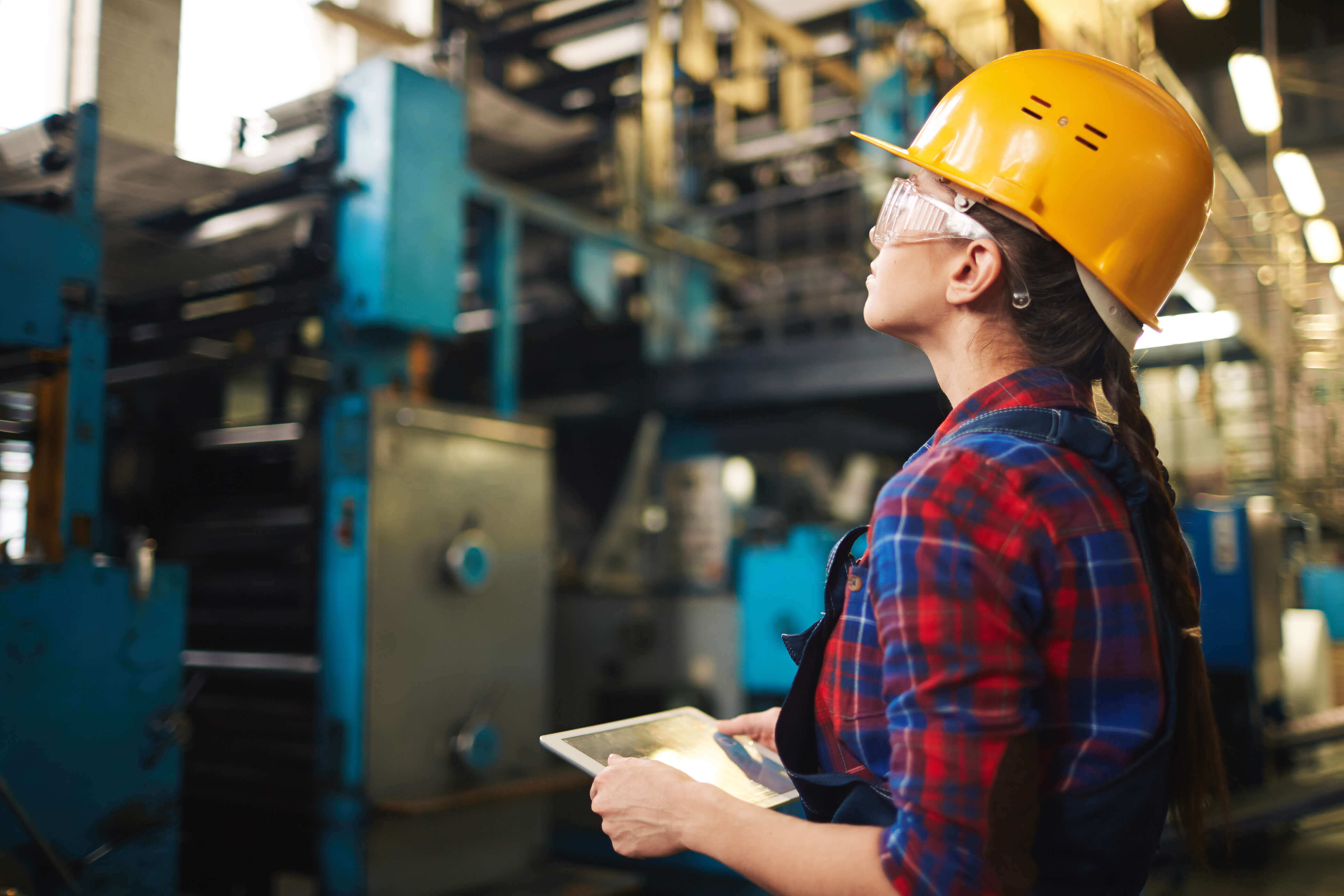 Woman in a hard hat inspecting a machine