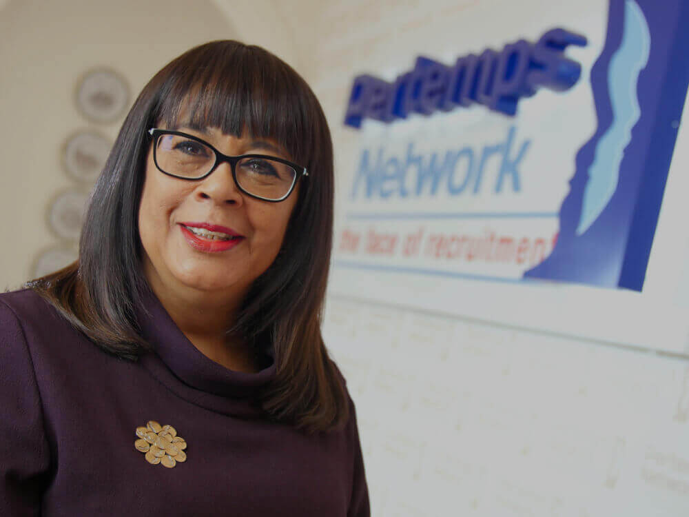 Carmen Watson stood by a large Pertemps sign