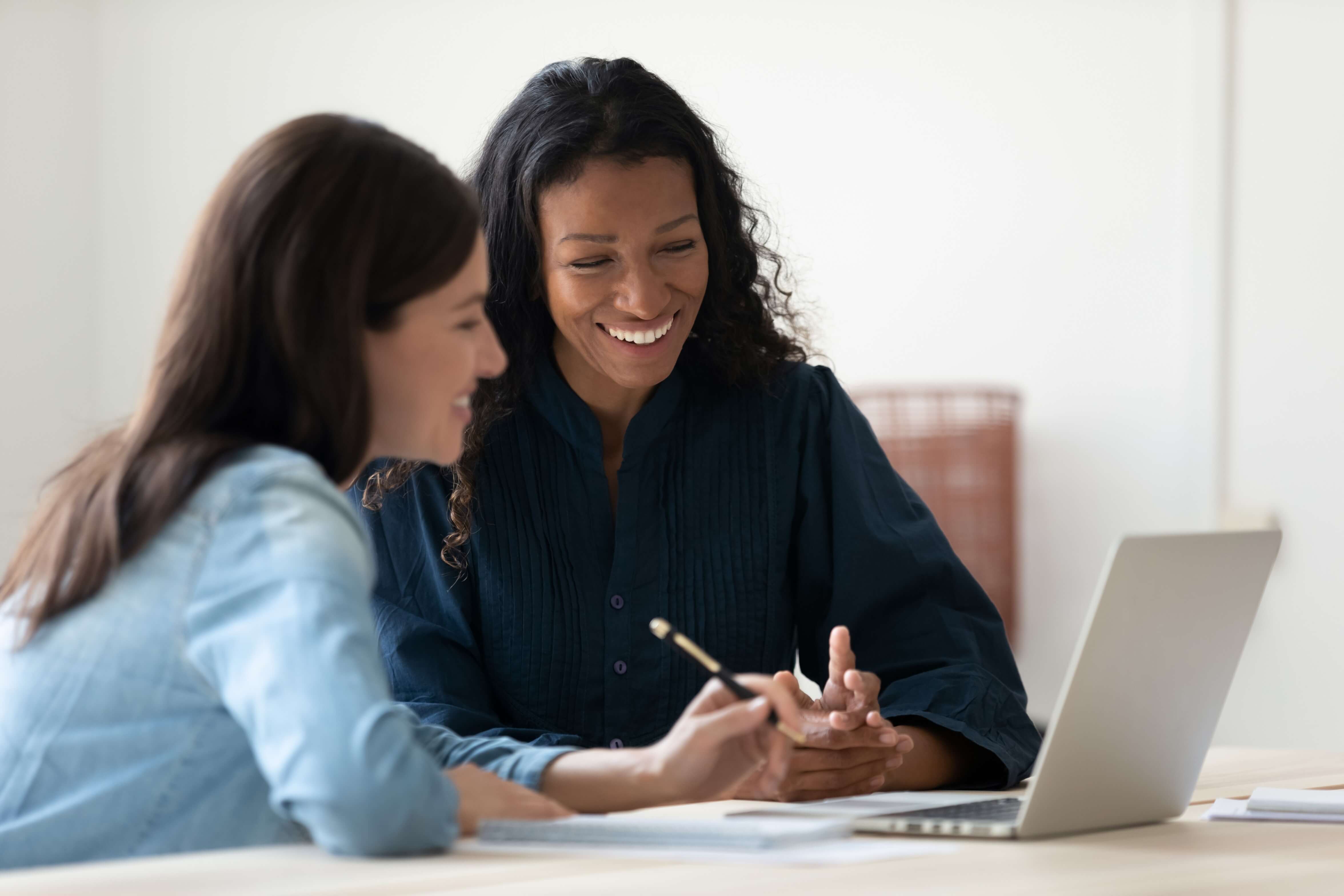 two women smiling at laptop